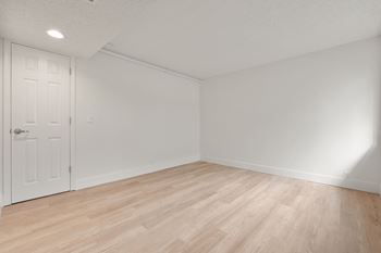 Empty room with white door and wooden floor